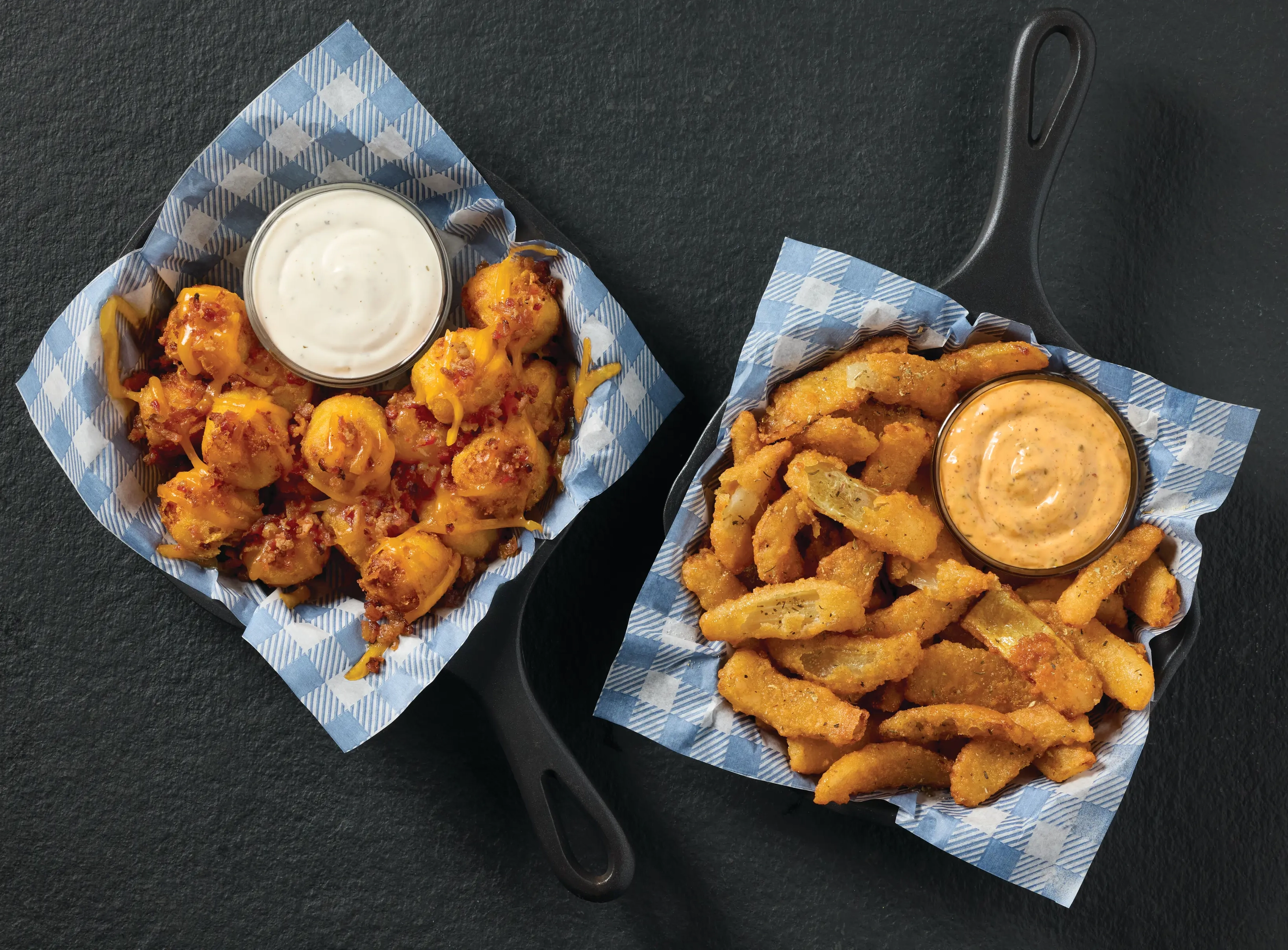 Onion petals and loaded tater tots served in skillets with dipping sauces.